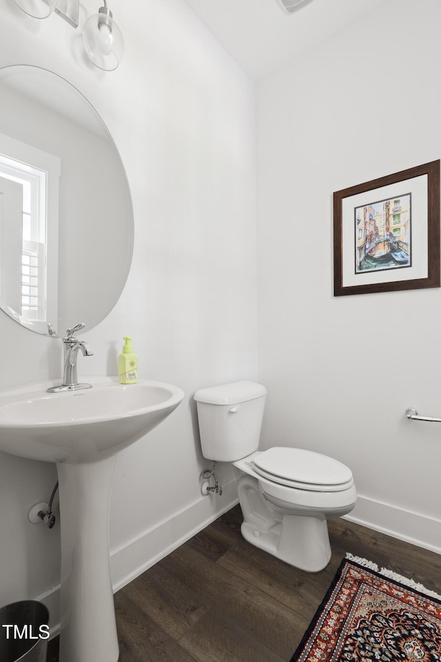 bathroom with baseboards, wood finished floors, visible vents, and toilet