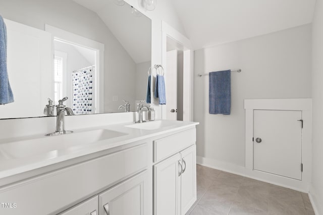 bathroom featuring double vanity, tile patterned flooring, a sink, and lofted ceiling
