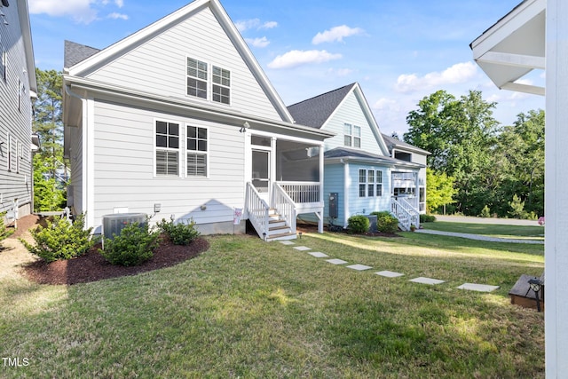 back of property featuring a lawn, roof with shingles, a sunroom, and cooling unit