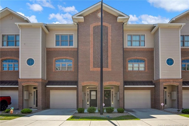 multi unit property with a standing seam roof, an attached garage, driveway, and brick siding