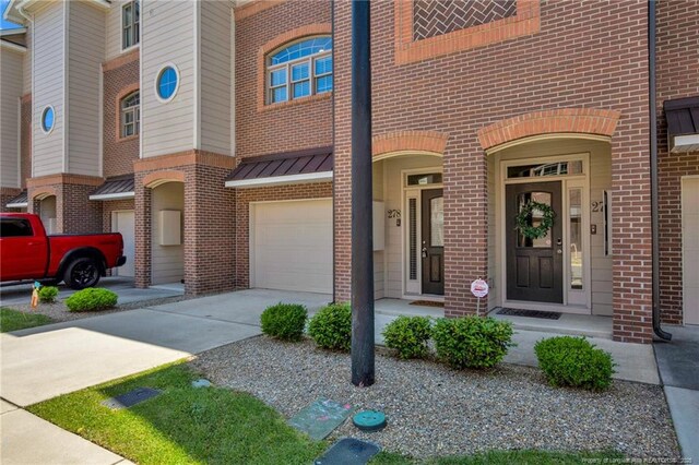 278 Hugh Shelton Loop, Fayetteville, NC 28301 - view of exterior entry featuring a garage, a standing seam roof, concrete driveway, and brick siding