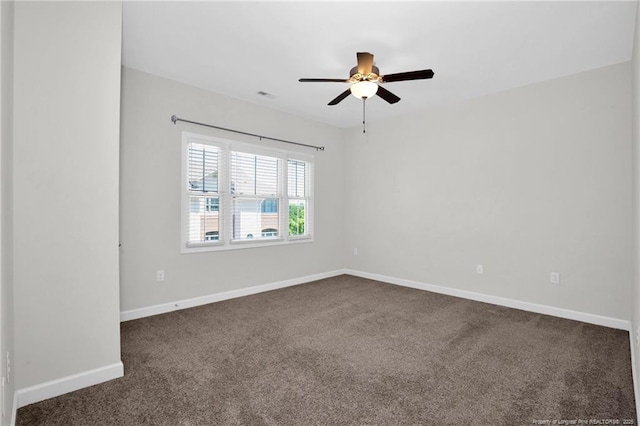 empty room featuring dark carpet, baseboards, ceiling fan, and visible vents