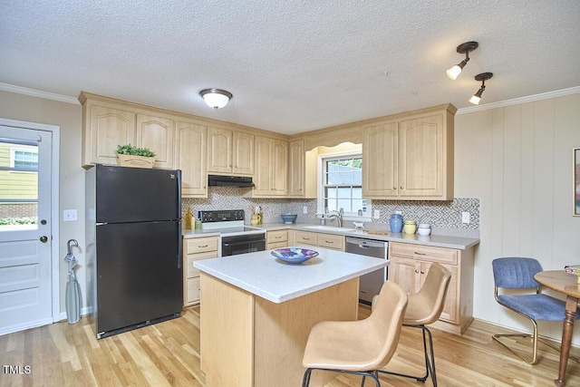 kitchen featuring light brown cabinetry, electric range oven, stainless steel dishwasher, freestanding refrigerator, and under cabinet range hood