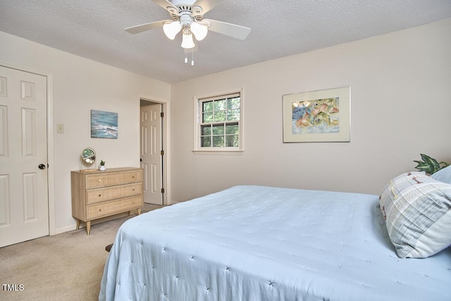 bedroom with a ceiling fan, a textured ceiling, and light carpet