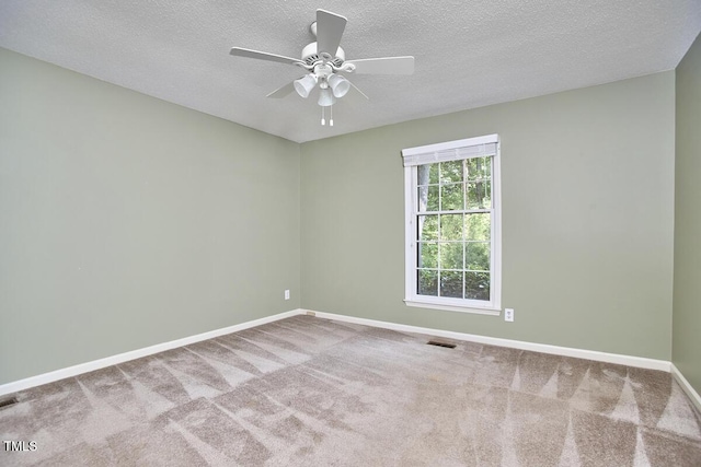 carpeted spare room featuring baseboards, a ceiling fan, a textured ceiling, and visible vents