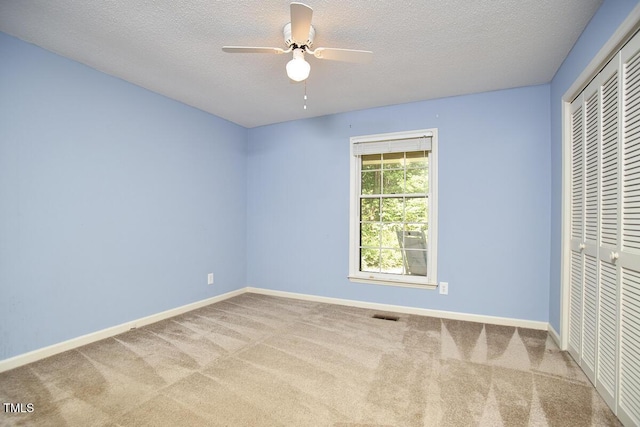 unfurnished bedroom featuring carpet floors, a textured ceiling, baseboards, and a closet