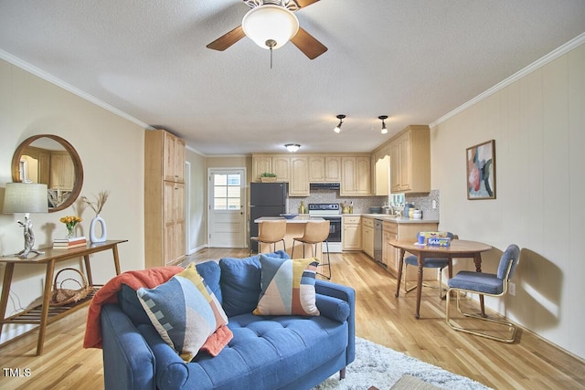 living room with a textured ceiling, ornamental molding, light wood-type flooring, and ceiling fan