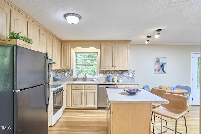 kitchen featuring dishwasher, light countertops, light brown cabinets, freestanding refrigerator, and range with electric stovetop