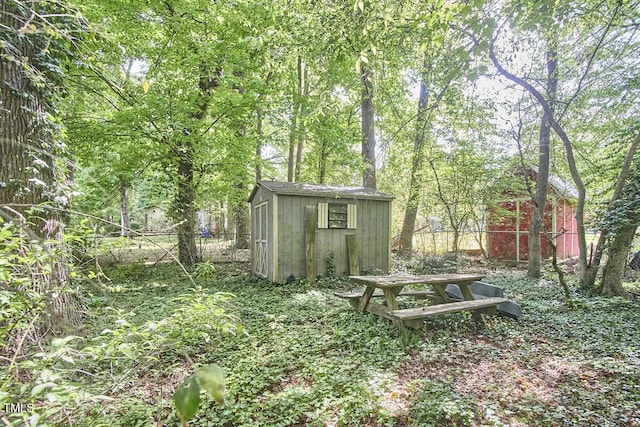 view of yard with fence, a storage unit, and an outdoor structure