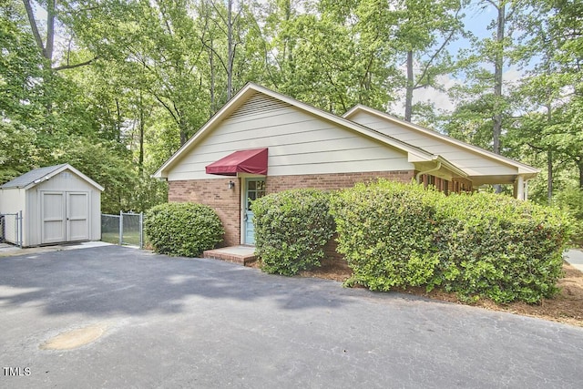 view of property exterior with brick siding, fence, an outbuilding, and a storage unit