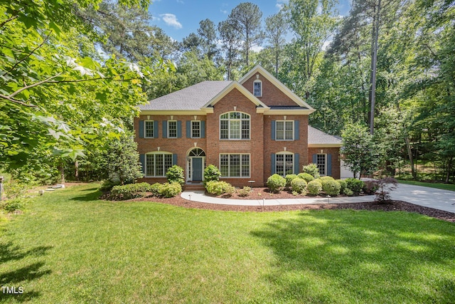 8840 Woodyhill Rd, Raleigh, NC 27613 - colonial-style house with a front yard, brick siding, roof with shingles, and concrete driveway