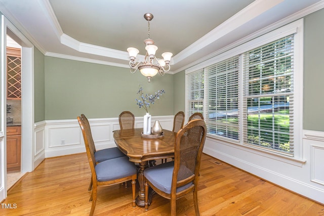 8840 Woodyhill Rd, Raleigh, NC 27613 - dining area with a chandelier, a raised ceiling, ornamental molding, healthy amount of natural light, and a wainscoted wall