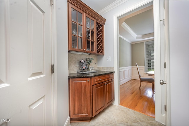 8840 Woodyhill Rd, Raleigh, NC 27613 - indoor dry bar featuring crown molding, light tile patterned floors, decorative backsplash, a wainscoted wall, and a raised ceiling
