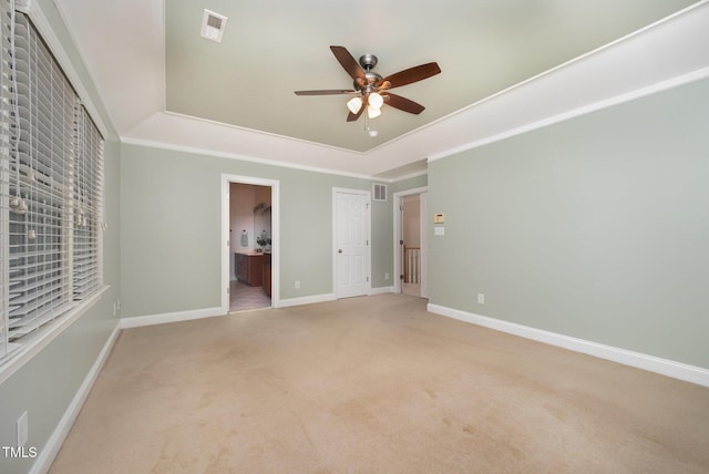 8840 Woodyhill Rd, Raleigh, NC 27613 - unfurnished bedroom with light colored carpet, baseboards, a tray ceiling, ensuite bathroom, and a ceiling fan
