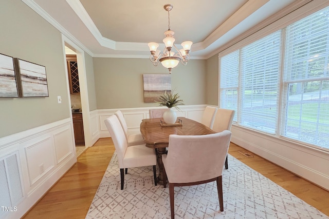 8840 Woodyhill Rd, Raleigh, NC 27613 - dining area featuring a raised ceiling, a chandelier, light wood finished floors, a decorative wall, and a wainscoted wall