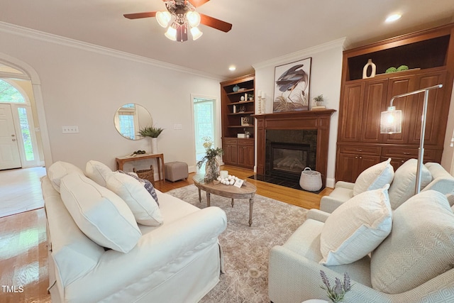 8840 Woodyhill Rd, Raleigh, NC 27613 - living area featuring ceiling fan, crown molding, a fireplace with flush hearth, light wood-style floors, and built in shelves