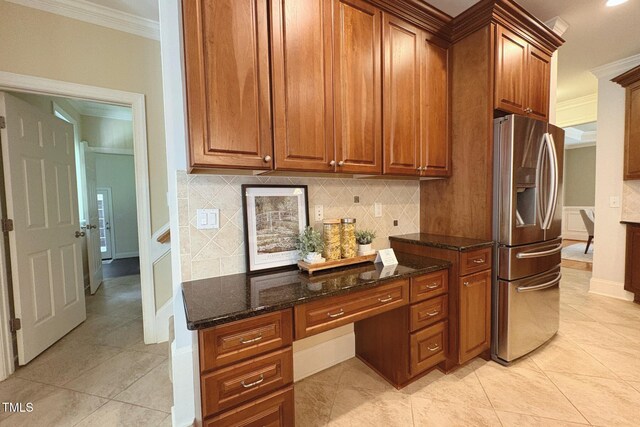 8840 Woodyhill Rd, Raleigh, NC 27613 - kitchen featuring stainless steel refrigerator with ice dispenser, ornamental molding, built in desk, tasteful backsplash, and dark stone counters