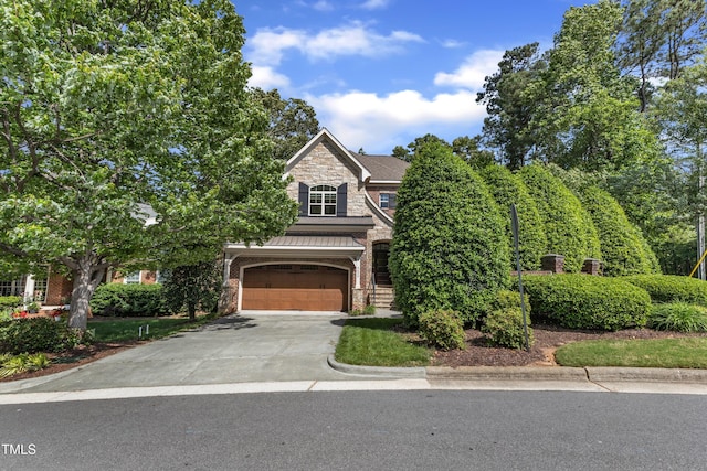 obstructed view of property featuring a standing seam roof, brick siding, concrete driveway, an attached garage, and stone siding