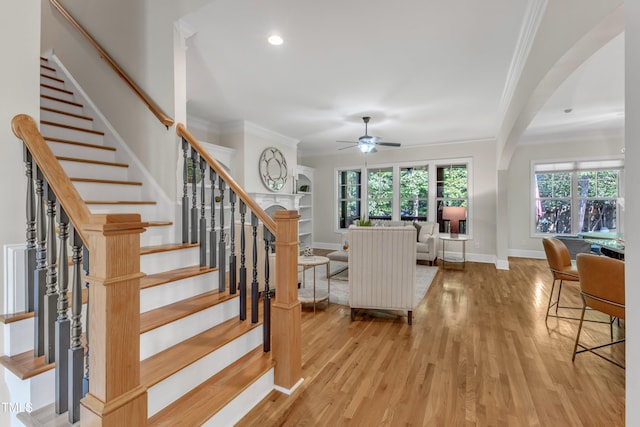 stairway with plenty of natural light, ceiling fan, and wood finished floors