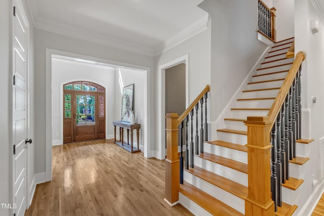 entryway featuring crown molding, baseboards, wood finished floors, and stairway