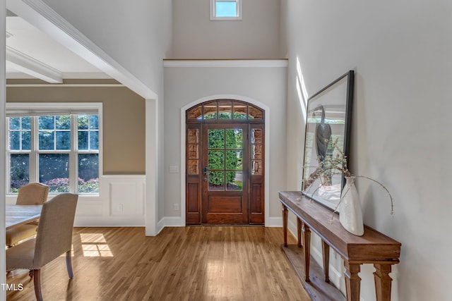 foyer entrance with baseboards, wood finished floors, and a towering ceiling