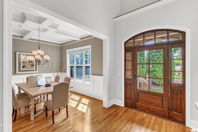 entrance foyer featuring crown molding, beam ceiling, a notable chandelier, light wood-style floors, and coffered ceiling