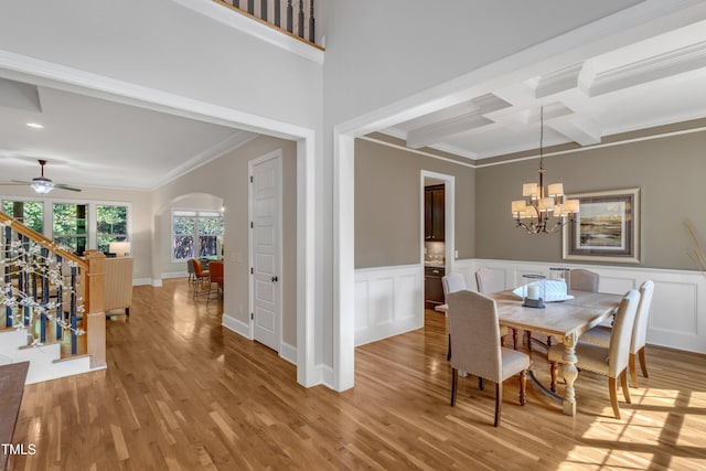 dining area with crown molding, arched walkways, light wood-type flooring, beam ceiling, and coffered ceiling