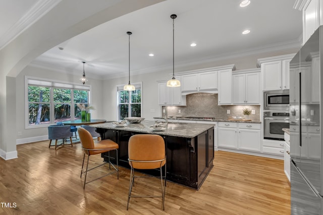 kitchen with light wood-style flooring, tasteful backsplash, light stone countertops, and stainless steel appliances