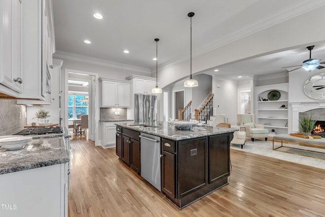 kitchen featuring dark brown cabinets, a warm lit fireplace, white cabinetry, light wood finished floors, and stainless steel appliances