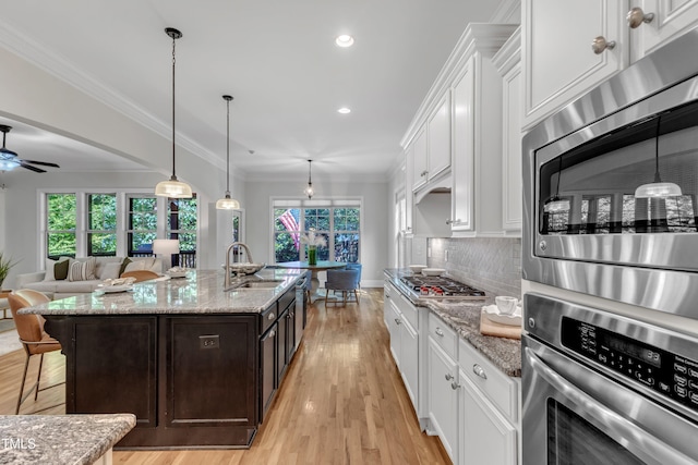 kitchen featuring dark brown cabinets, a kitchen bar, white cabinets, a sink, and stainless steel appliances