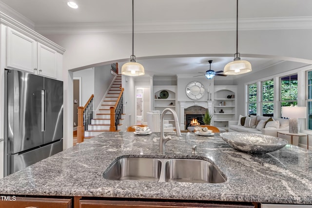 kitchen featuring a ceiling fan, ornamental molding, stainless steel fridge, and a sink