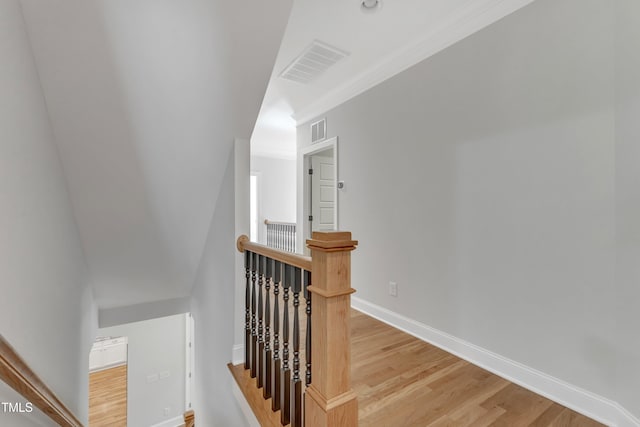 stairs with baseboards, wood finished floors, and visible vents