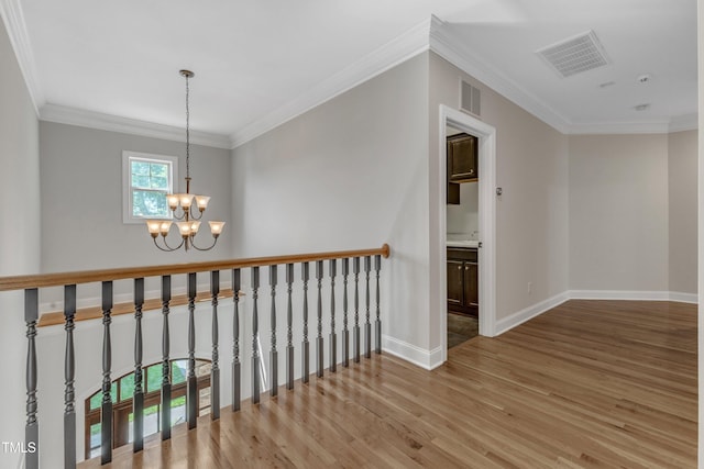 hallway with wood finished floors, baseboards, a chandelier, and visible vents
