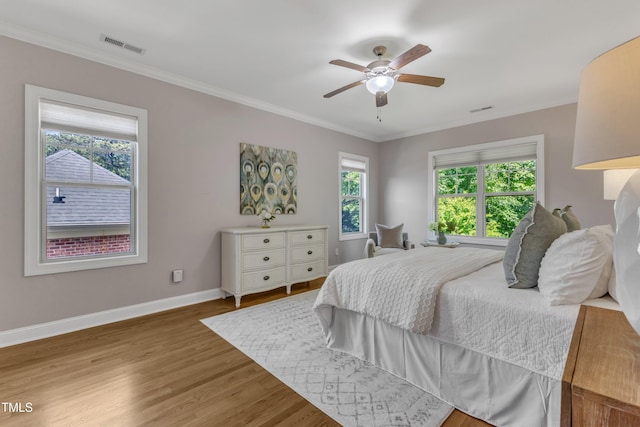 bedroom with baseboards, multiple windows, wood finished floors, and visible vents