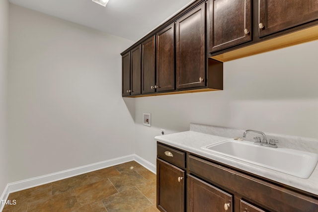 washroom featuring baseboards, hookup for a washing machine, a sink, cabinet space, and hookup for an electric dryer