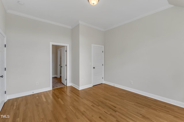 unfurnished bedroom with baseboards, ornamental molding, and light wood-style floors