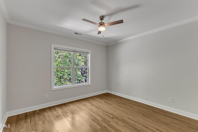 empty room with visible vents, ornamental molding, wood finished floors, baseboards, and ceiling fan