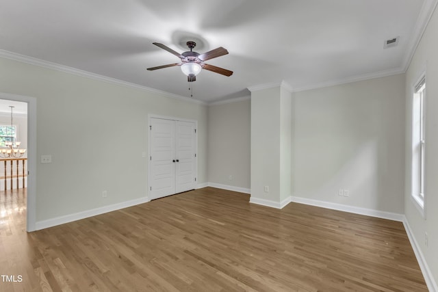 empty room featuring baseboards, ornamental molding, wood finished floors, and ceiling fan with notable chandelier