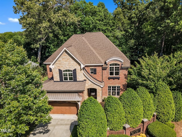 view of front of house with stone siding, brick siding, a shingled roof, an attached garage, and driveway
