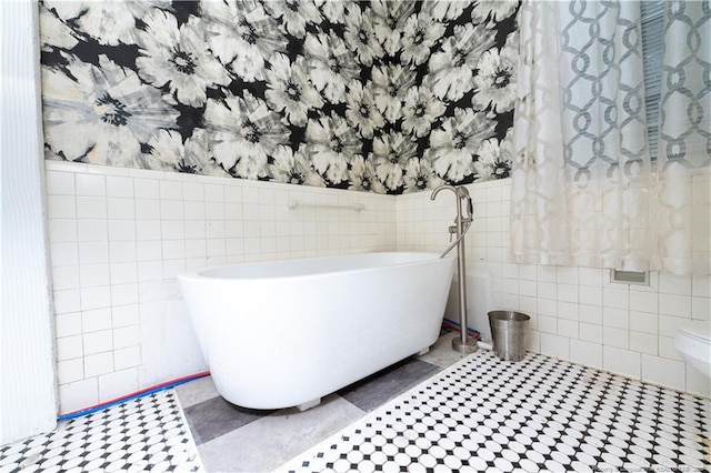 236 E Andrews Ave, Henderson, NC 27536 - bathroom with a freestanding bath, tile walls, a wainscoted wall, and wallpapered walls
