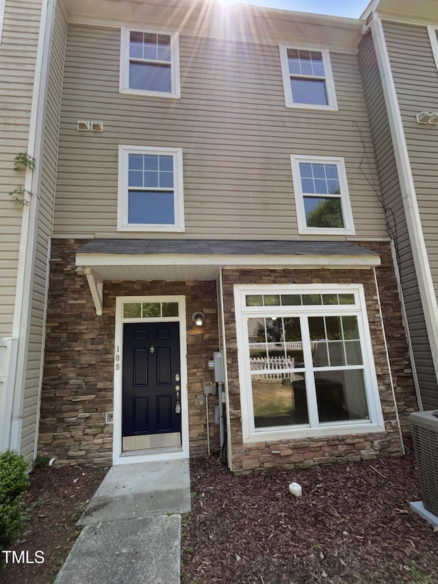 view of exterior entry with central AC unit and stone siding