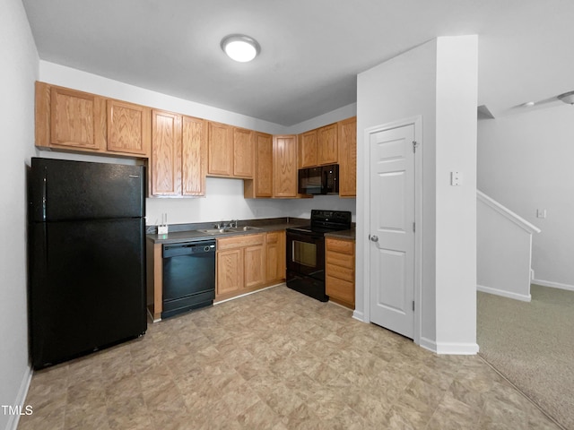 kitchen with dark countertops, baseboards, light floors, a sink, and black appliances