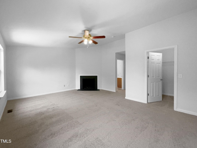unfurnished living room featuring ceiling fan, carpet, baseboards, a fireplace with flush hearth, and visible vents