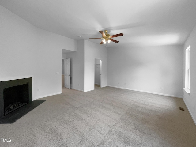 unfurnished living room with carpet flooring, a ceiling fan, baseboards, and a fireplace with flush hearth
