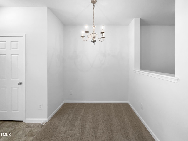 carpeted empty room with baseboards and a chandelier