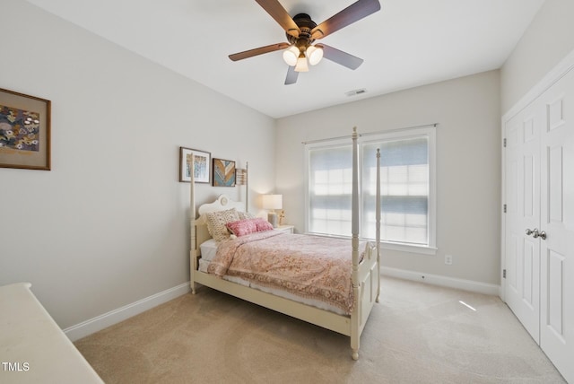 bedroom featuring visible vents, a closet, light carpet, baseboards, and ceiling fan