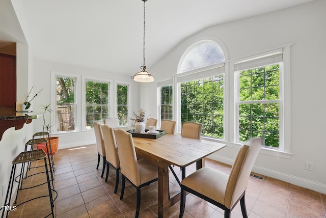 dining area featuring tile patterned floors, vaulted ceiling, and a healthy amount of sunlight