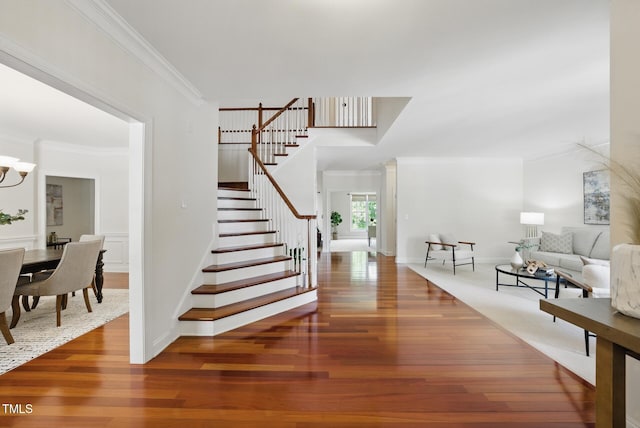 interior space featuring baseboards, ornamental molding, wood finished floors, and a notable chandelier