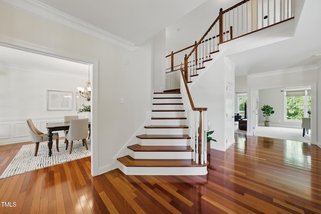 staircase featuring ornamental molding, a chandelier, and hardwood / wood-style flooring