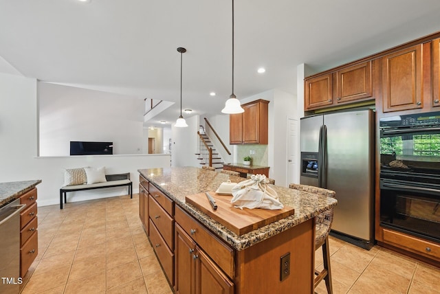 kitchen with brown cabinets, appliances with stainless steel finishes, a kitchen breakfast bar, a center island, and light tile patterned floors